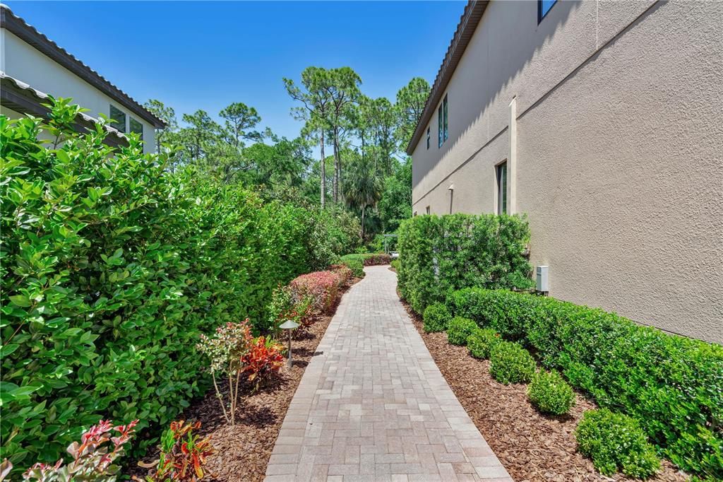 Meticulously landscaped pavered pathway leading to the backyard oasis