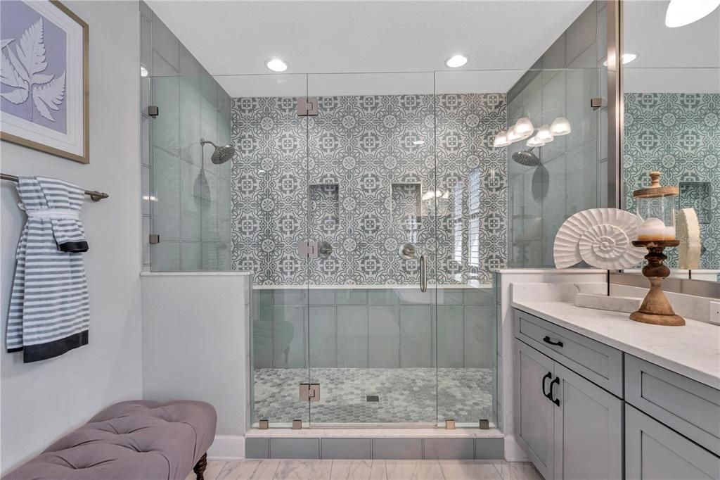 Spacious shower with dual shower heads and custom glass tile
