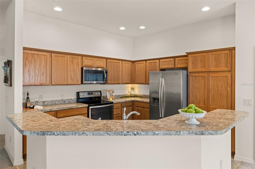 Large kitchen features an abundance of cabinet space, Stainless Steel appliances, a double-door pantry, and a spacious breakfast bar for casual dining.