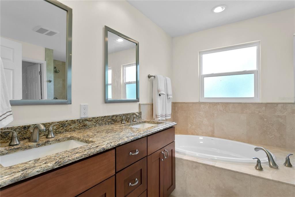 The primary bathroom features dual vanity sinks, a large soaking tub and shower with a separate water closet