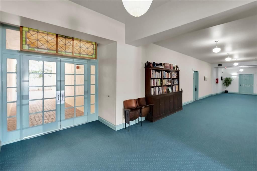 Hallway, past bookshelf (lending library) next door is the unit. Door you see goes to courtyard. There is another door like that to the right and it is the front main entrance out to Mirror Lake