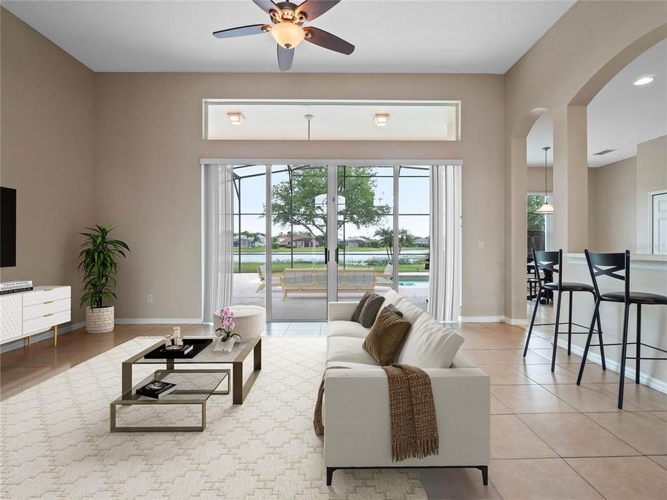 The spacious living area is open to the kitchen with a WALL OF SLIDING GLASS DOORS that access the covered lanai and screened pool for indoor/outdoor living and sweeping VIEWS OF THE WATER! Virtually Staged.