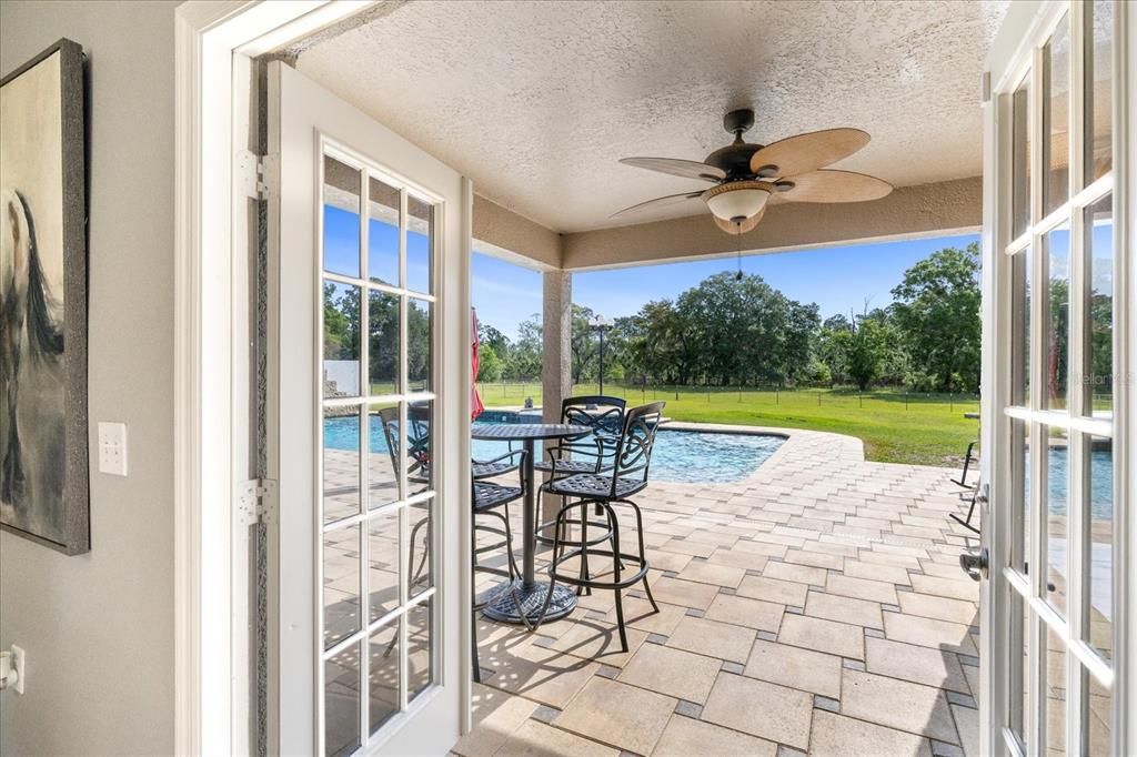 French doors lead to outdoor kitchen, pool, spa, waterfall