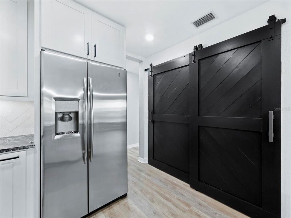 Stylish sliding barn-style doors enhance the large pantry in the kitchen