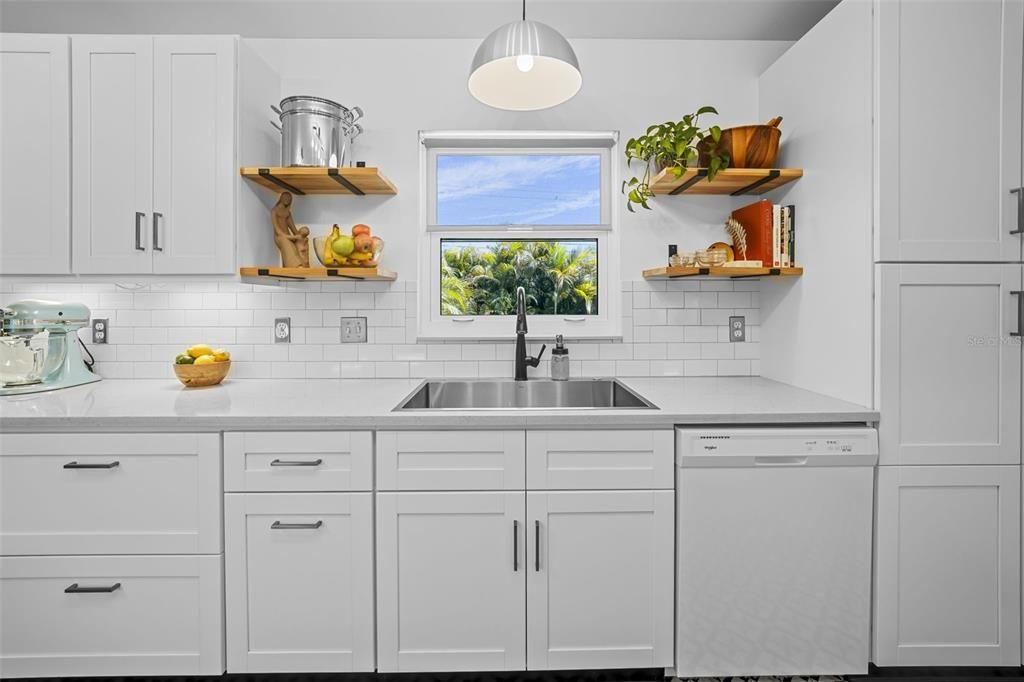white raised-panel cabinetry w/new hardware, white subway backsplash, Quartzite countertops, farm-style sink