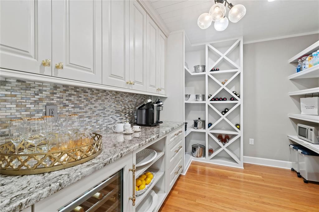 Walk-in pantry with custom cabinetry, wine fridge and granite counters