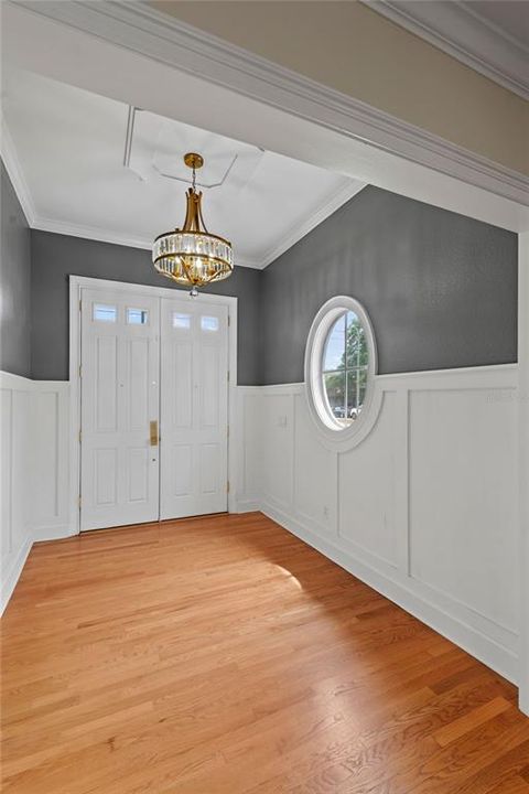 Welcoming foyer with crown molding and wainscoting