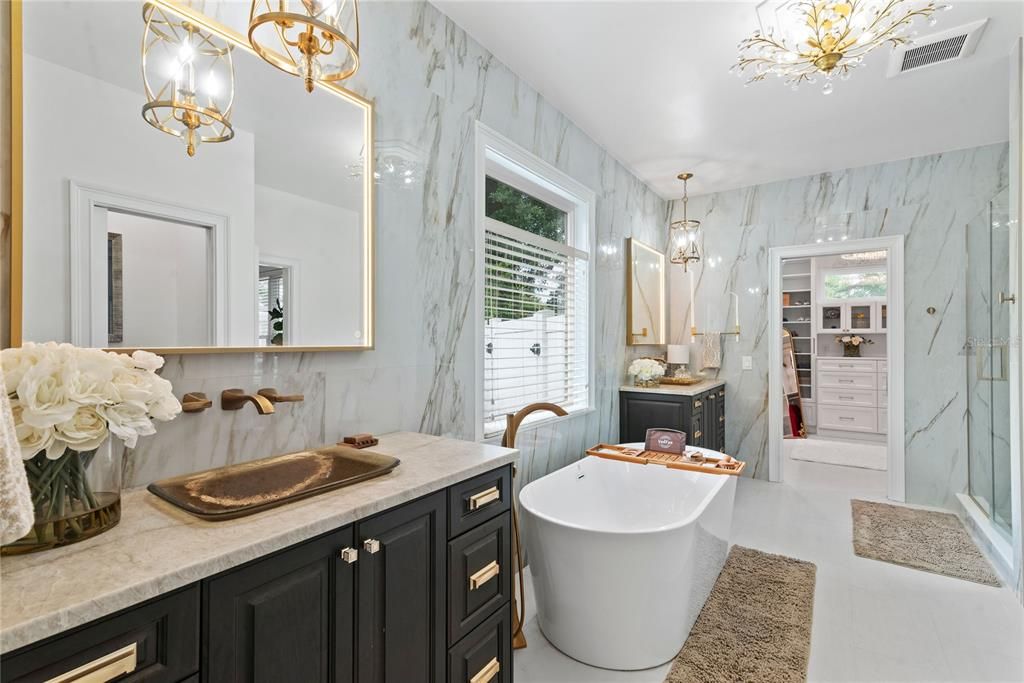 Gorgeous primary bathroom with dual vanities with leathered finish granite counters, soak tub, walk-in glass-enclosed shower, toilet closet with Toto toilet, Kohler faucets and two California closets.