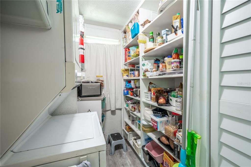 The laundry room comes with a stackable washer/dryer and has pantry shelving for additional storage.