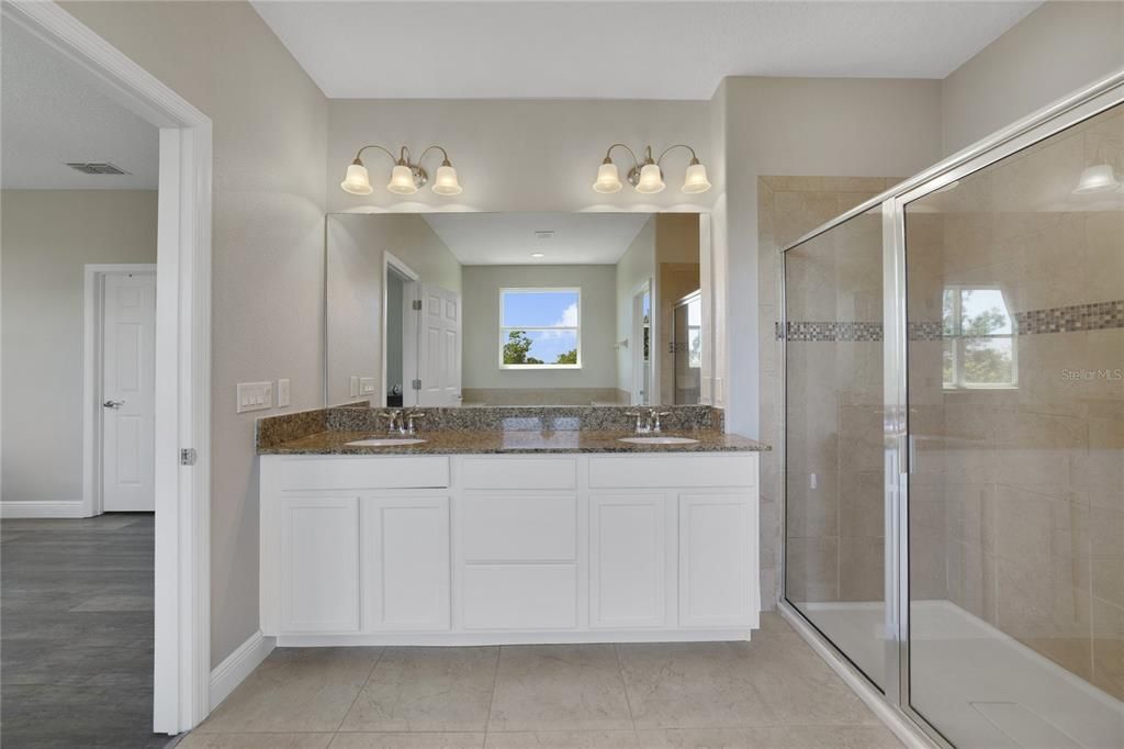 Private en-suite bath delivers a dual sink vanity, SOAKING TUB and separate glass enclosed shower.