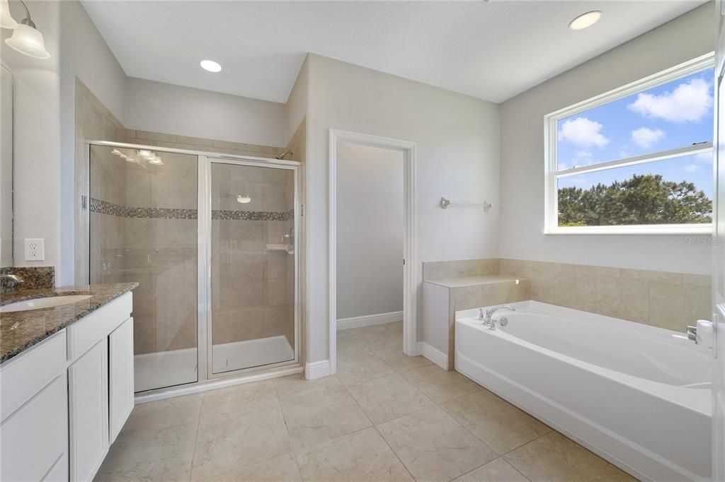 Private en-suite bath delivers a dual sink vanity, SOAKING TUB and separate glass enclosed shower.