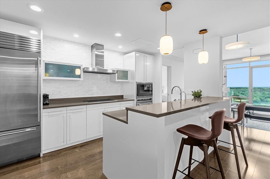 Clean, crisp, modern and neutral kitchen, backsplash wraps to the top. SUB ZERO fridge, EUROPEAN cabinetry that lift open on pistons, slim lined hood, and WOLF cooktop, oven, microwave.