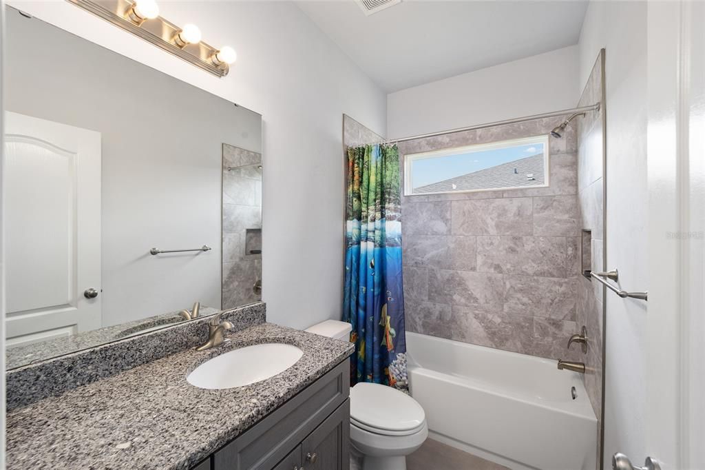 Guest bathroom with granite countertops and tile shower/bath