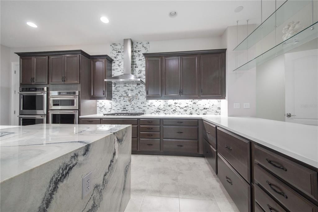 Chef's Kitchen features Waterfall Edge Quartzite Island, Pot Filler, Gas Stove with Stainless Steel Hood and Upgraded Cabinetry .