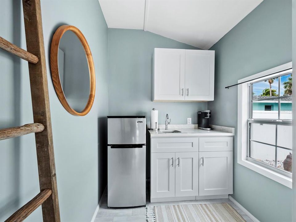 The kitchenette has cabinet and counter space with a bar style sink and small refrigerator and freezer.