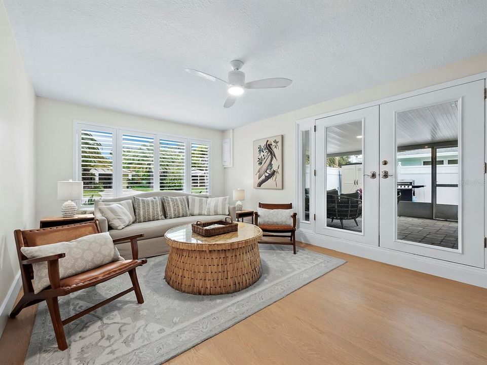 The living room features beautiful bay windows with built in seating and French doors leading to the screened lanai.