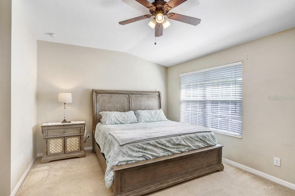 The master suite features a walk-in closet, a lighted ceiling fan, and a large window that overlooks the front of the home.