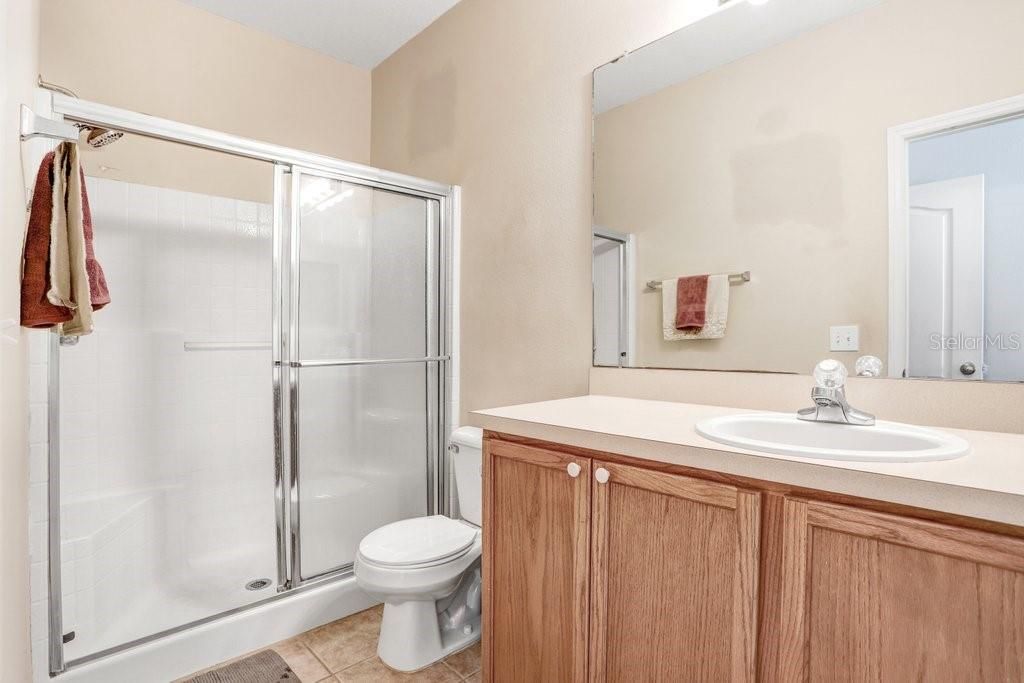 The master ensuite features a walk-in shower, ample cabinet storage, and ceramic tile floors.