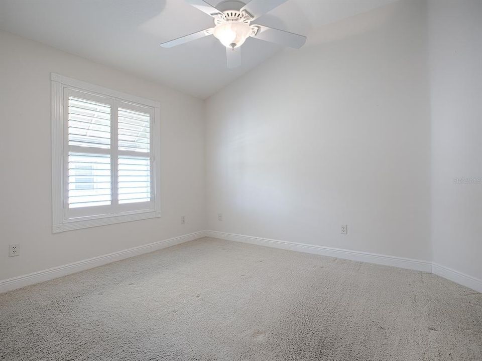 2ND GUEST ROOM WITH CARPET, VAULTED CEILINGS, CEILING FAN, AND PLANTATION SHUTTERS.