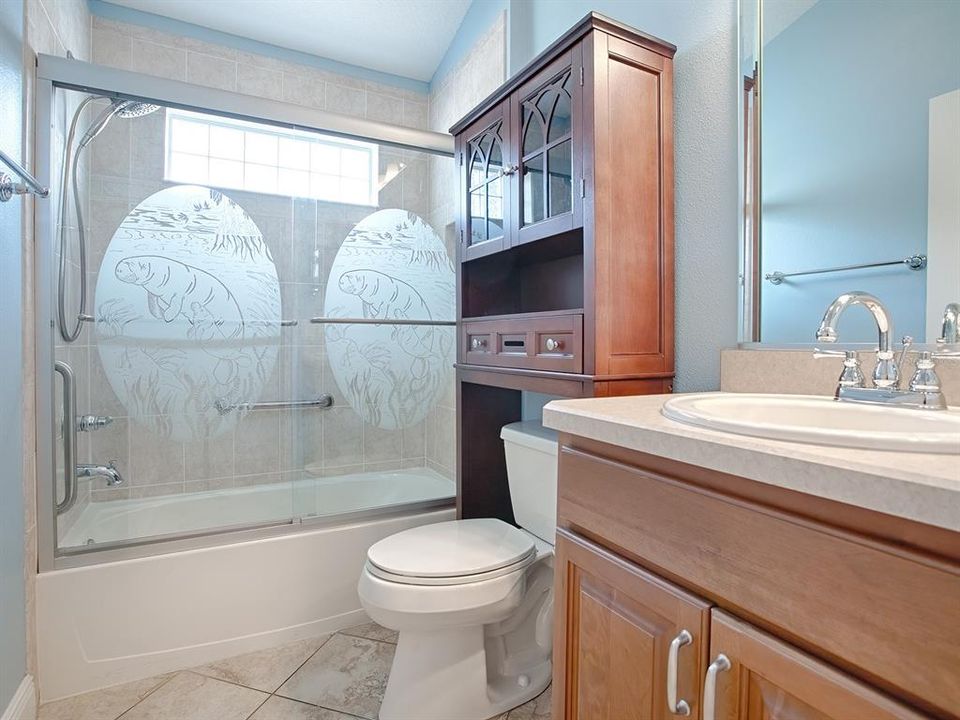 GUEST BATH WITH TUB/SHOWER AND GLASS ENCLOSURE. BEVELED-EDGE MIRROR AND BEVELED-EDGE LAMINATE COUNTERS.