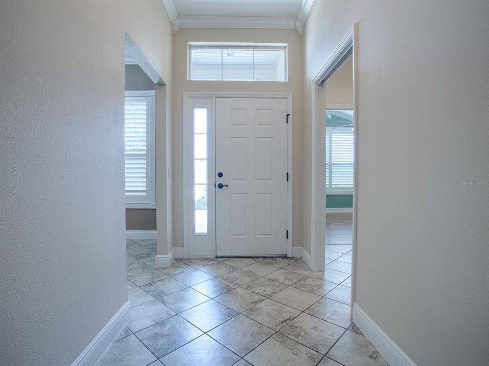 LOVELY FOYER WITH SIDELITE AND TRANSOM WITH PLANTATION SHUTTERS. DIAGONAL TILE THROUGHOUT MAIN LIVING AREA, KITCHEN AND HALLWAYS. NOTICE POCKET DOOR TO THE RIGHT LEADS TO THE GUEST SUITE.