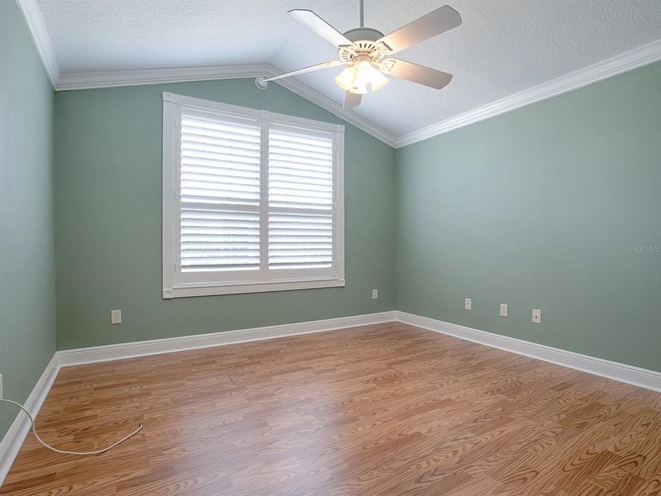 FRONT GUEST ROOM WITH LAMINATE FLOORING, PLANTATION SHUTTERS, CROWM MOLDING, VAULTED CEILINGS AND A CEILING FAN.  THIS ROOM DOES NOT HAVE A CLOSET.