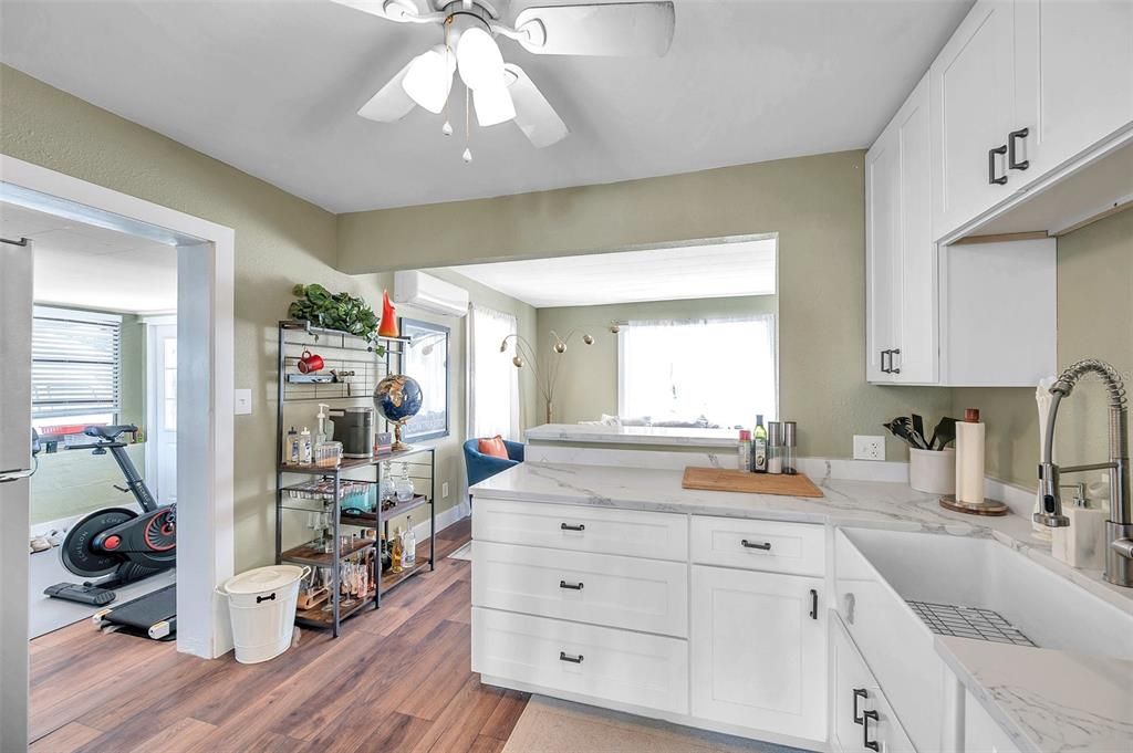 Shaker style cabinets and quartz counters in the living room that is open to the living room and leads to the bonus room