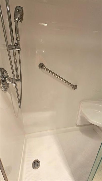 Newer handicap accessible shower with seat in primary bathroom.