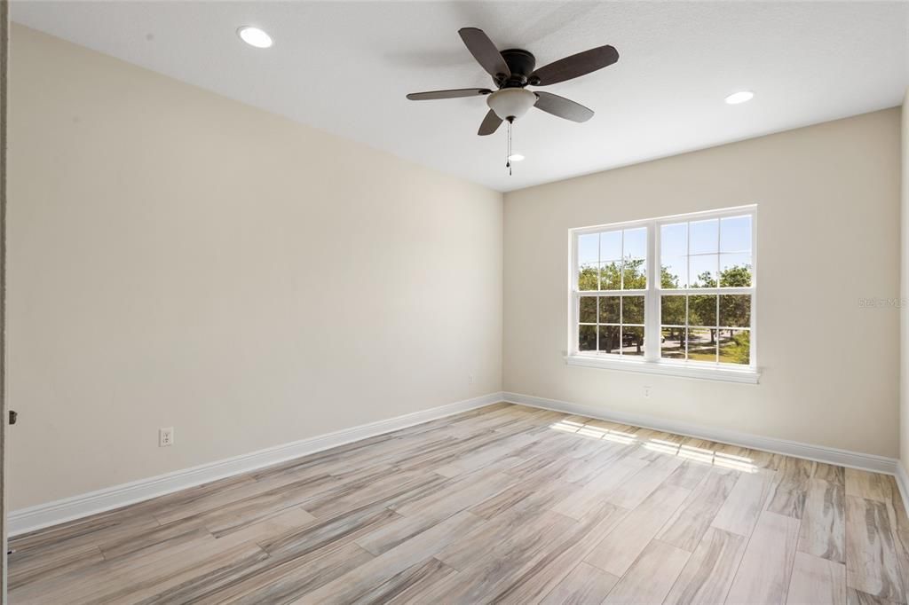 Bedroom 4 with ceiling fan overlooking the front of the home. Lovely pond views from the front of this home!