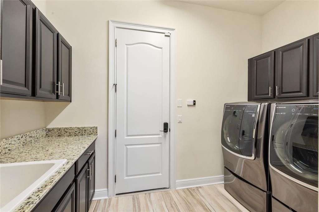 Laundry room with storage cabinets, laundry sink and newer LG signature washer and gas dryer in 2022 included and access to the 3 car garage!