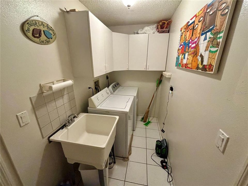 Inside Laundry with lots of storage cabinets and utility sink.