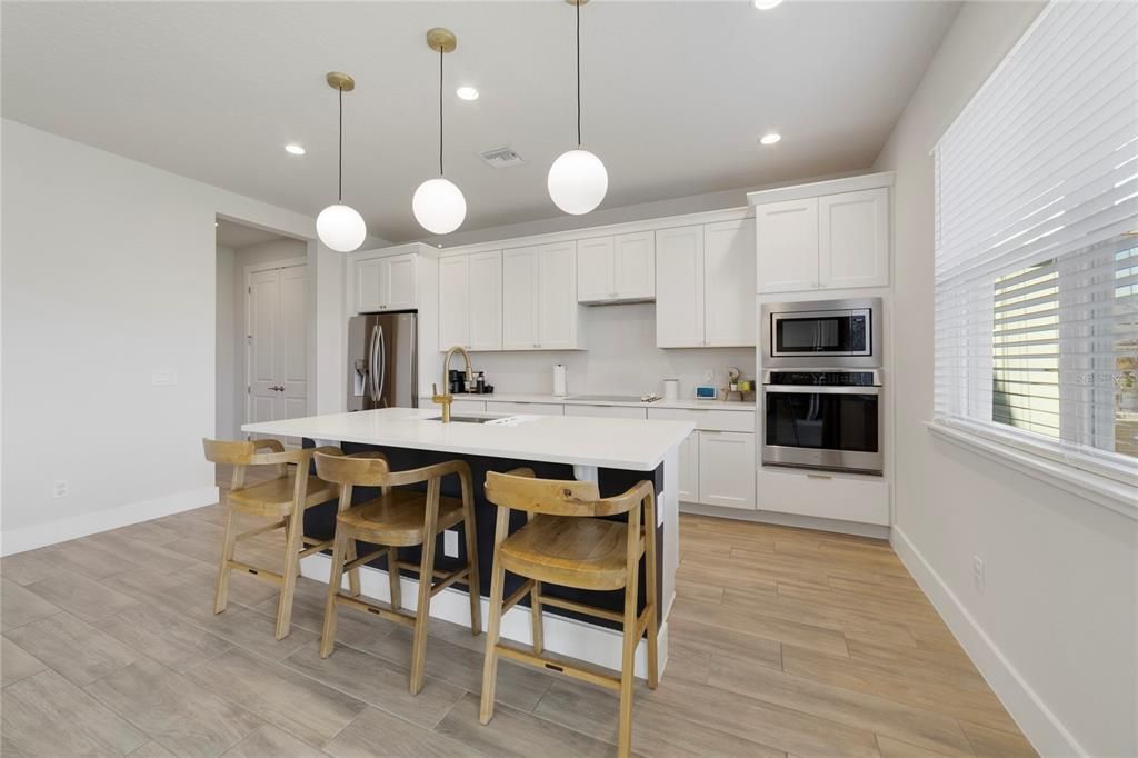 At the heart of it all you will find a home chef’s dream GOURMET KITCHEN featuring 42” SHAKER STYLE CABINETRY, solid surface counters, STAINLESS STEEL APPLIANCES and a large center island with breakfast bar seating under pendant lighting.