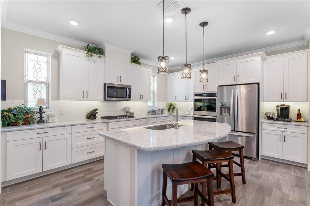 Dream Gourmet Kitchen with custom cabinetry, custom drawers with tongue in groove, gas cooktop, double convection wall ovens, fabulous walk in pantry with custom built ins and 2 custom stained glass inserts.