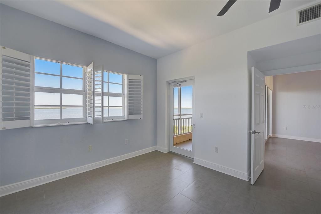 Picture Windows with Plantation Shutters in Primary Bedroom to Showcase Sweeping Bay Views