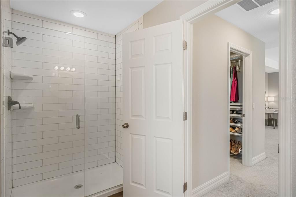 Glass walk-in shower and wood look tile floors in the en suite