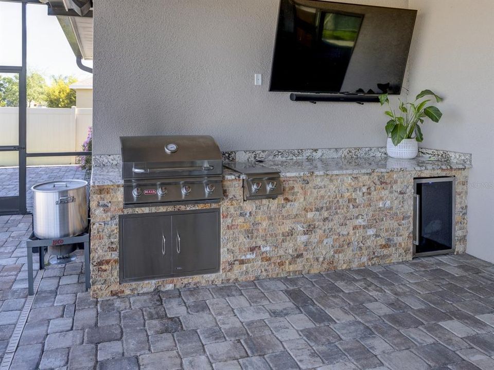 Outdoor kitchen. Granite counter top with grill, 2 burners and refrigerator.