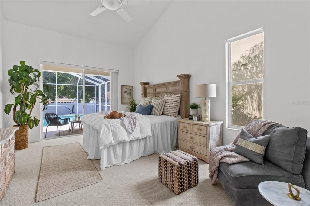 This beautiful master bedroom opens to the pool deck and look at that high ceiling!