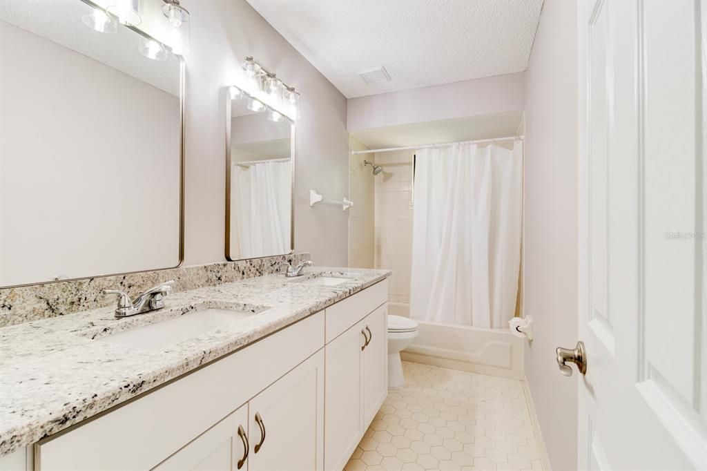 Guest bathroom has double sink vanity with tub and shower.