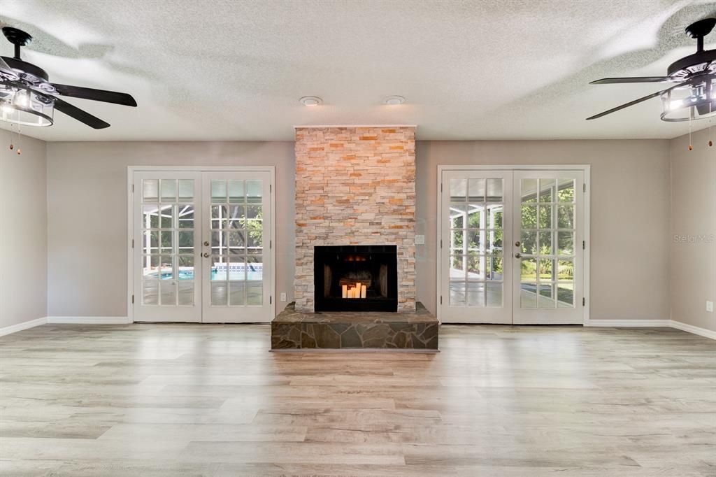 Beautiful stacked stone fireplace flanked by French doors to the pool area
