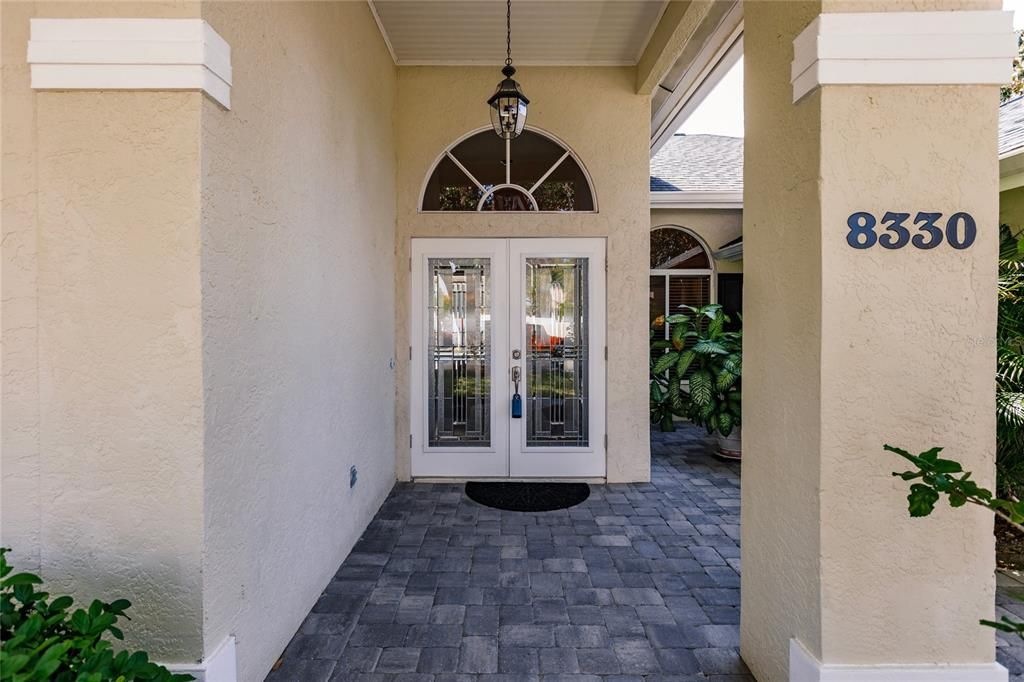 Beautiful leaded glass Double Entry Doors swing open wide in Foyer with living room, glimpse of Breakfast Room and pool beyond