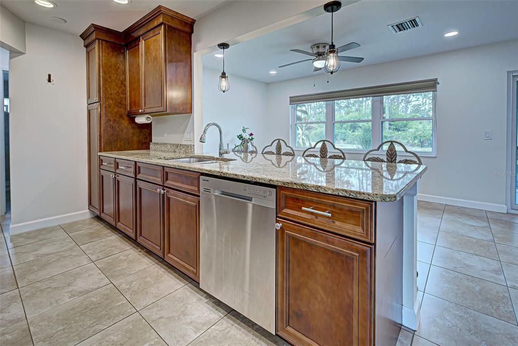 Beautiful kitchen features granite countertops, wood cabinets and classy pendant lighting.