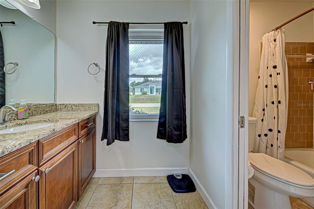 Ensuite bathroom with granite countertops and tub with shower.