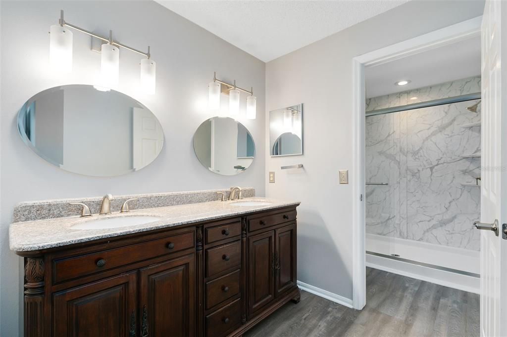 The updated ensuite master bath boasts a modern dual sink vanity and a luxurious walk-in shower.