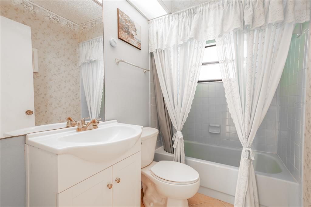 Bathroom 2 features a mirrored vanity with storage, ceramic tile floor and a tub with shower.