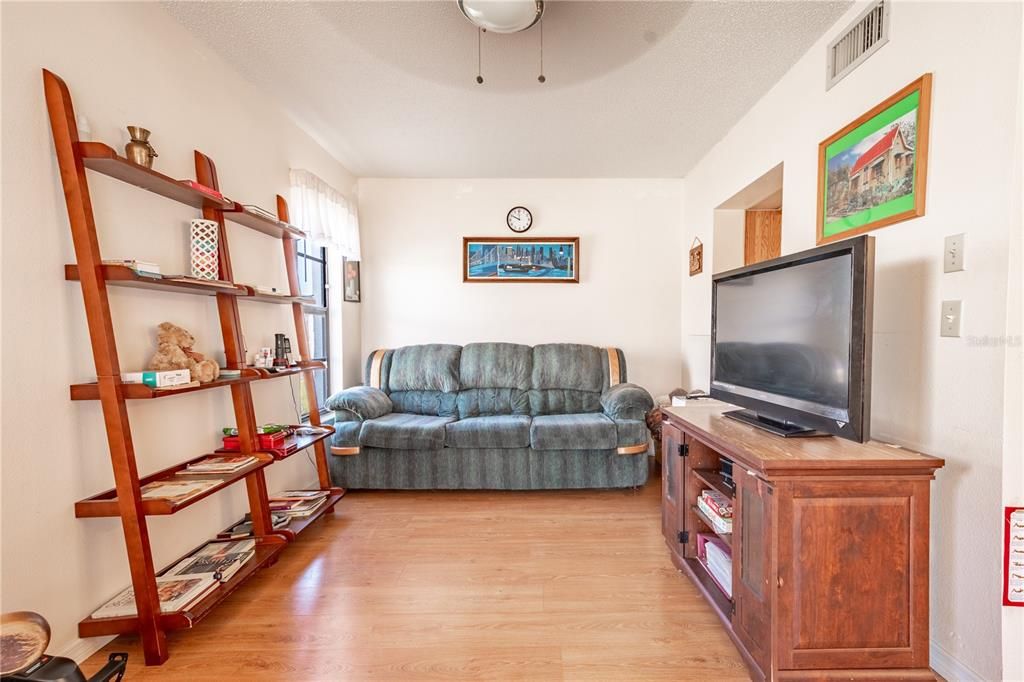 The Florida Room features wood laminate flooring, a ceiling fan and neutral tones.