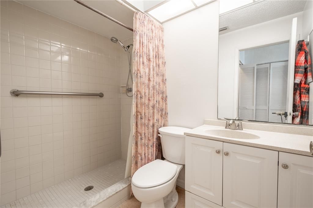 The primary bath features ceramic tile floor, large walk-in shower, amd a mirrored vanity with storage and overhead lighting.