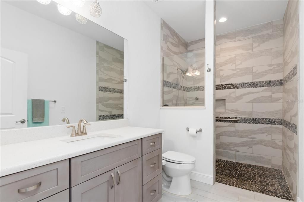 An extended vanity with extra counter space and storage coupled with the roll-in, accessible tiled shower invite you into your private sanctuary