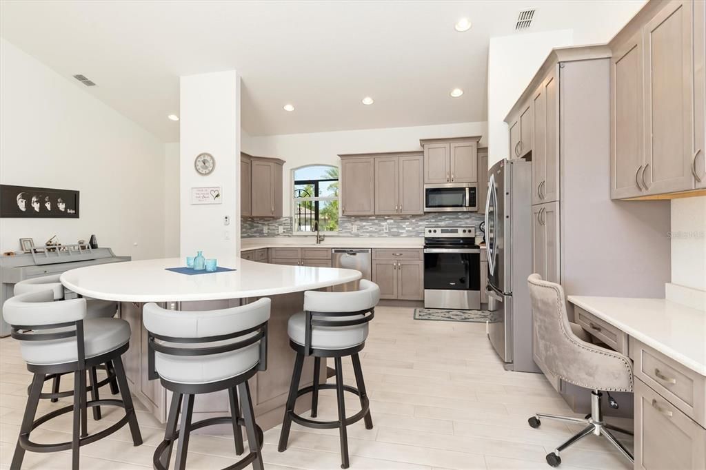 The custom-designed kitchen serves multiple purposes and includes a built-in desk/work area and expansive breakfast bar.