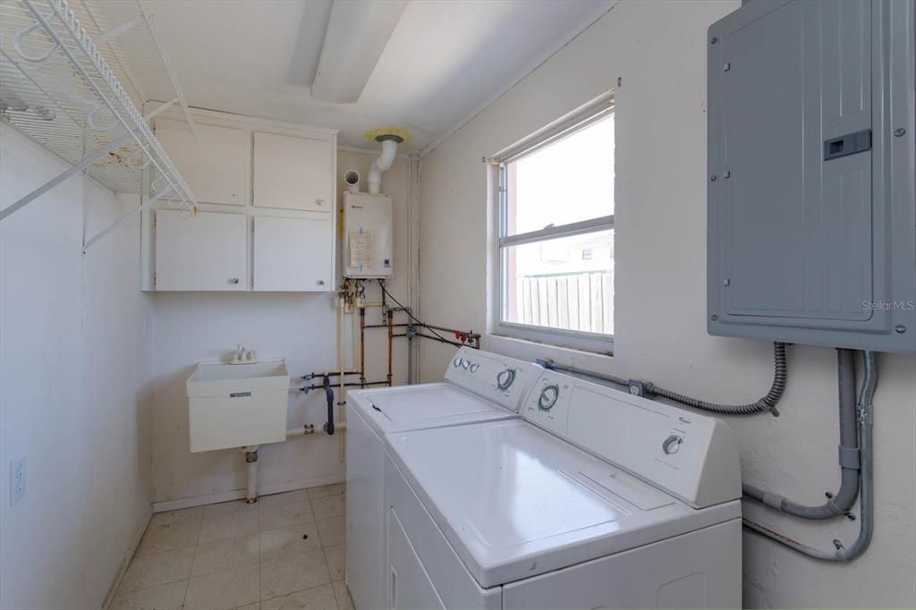 Laundry Room in the garage with tankless water heater and sink