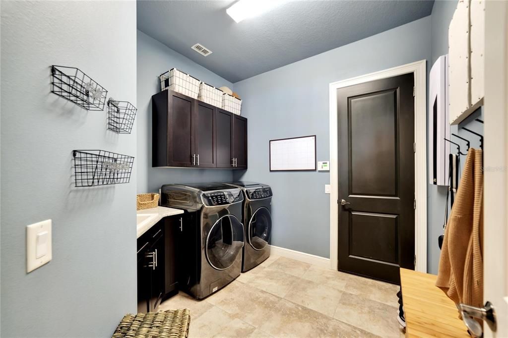 Laundry room with utility sink and entry door into garage
